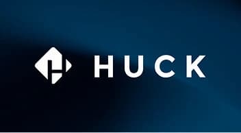 A white logo on a dark blue gradient background features the word "HUCK" in a bold, sans-serif typeface. To the left is an icon consisting of a diamond shape with a stylized "H" cut out of its center. A soft light beam provides a diagonal highlight across the scene.